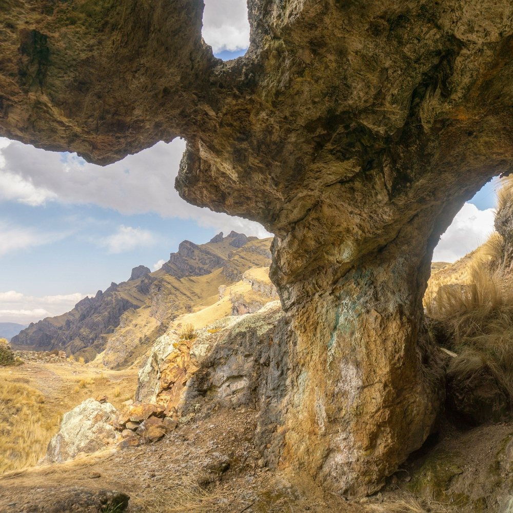 A natural rock arch opening onto a range of dry mountains.