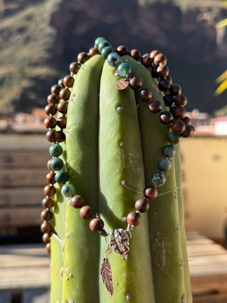 A strand of wooden prayer beads hung over a ribbed green column.